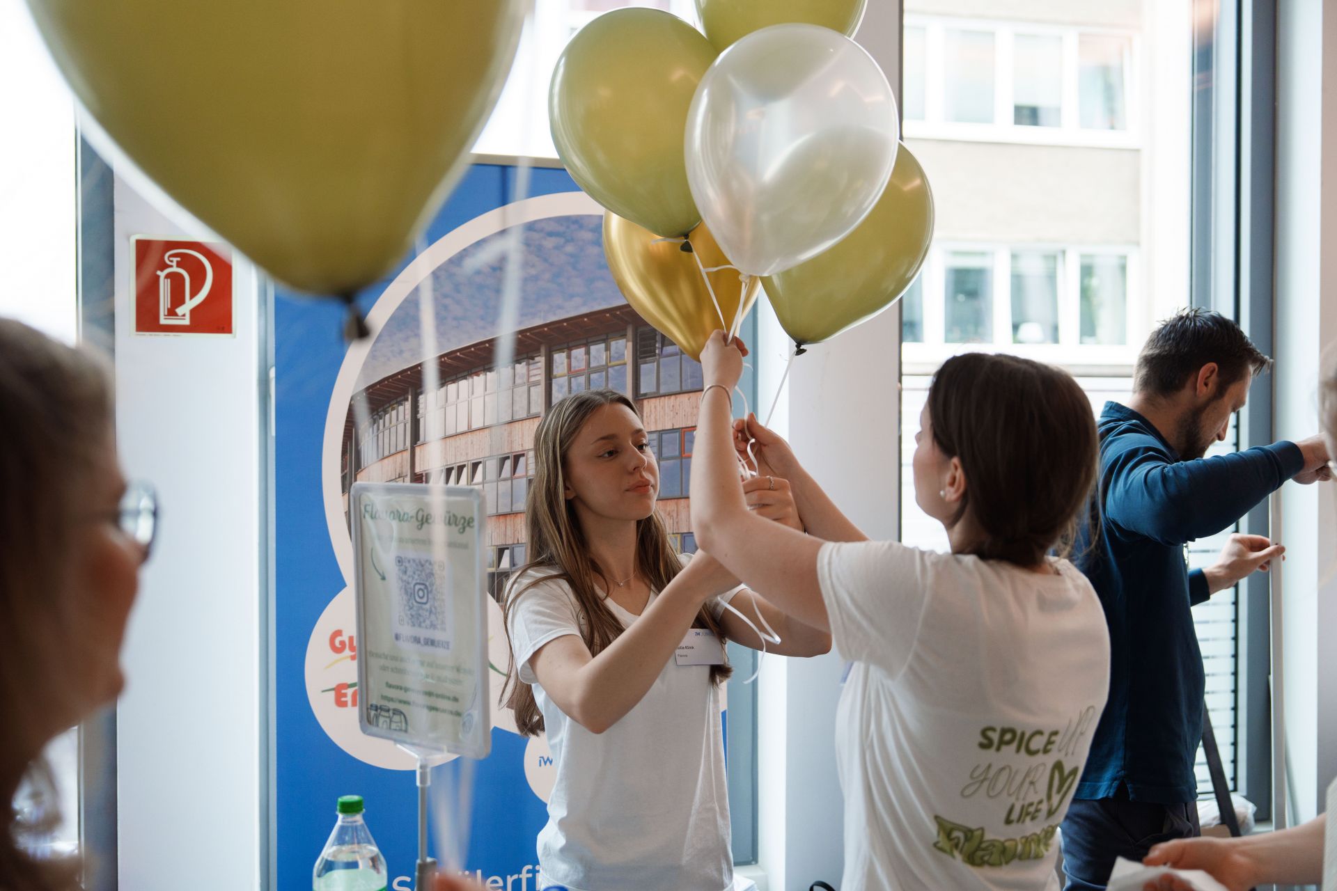 Zwei Schülerinnen platzieren zwei Luftballons für einen feierlichen Anlass